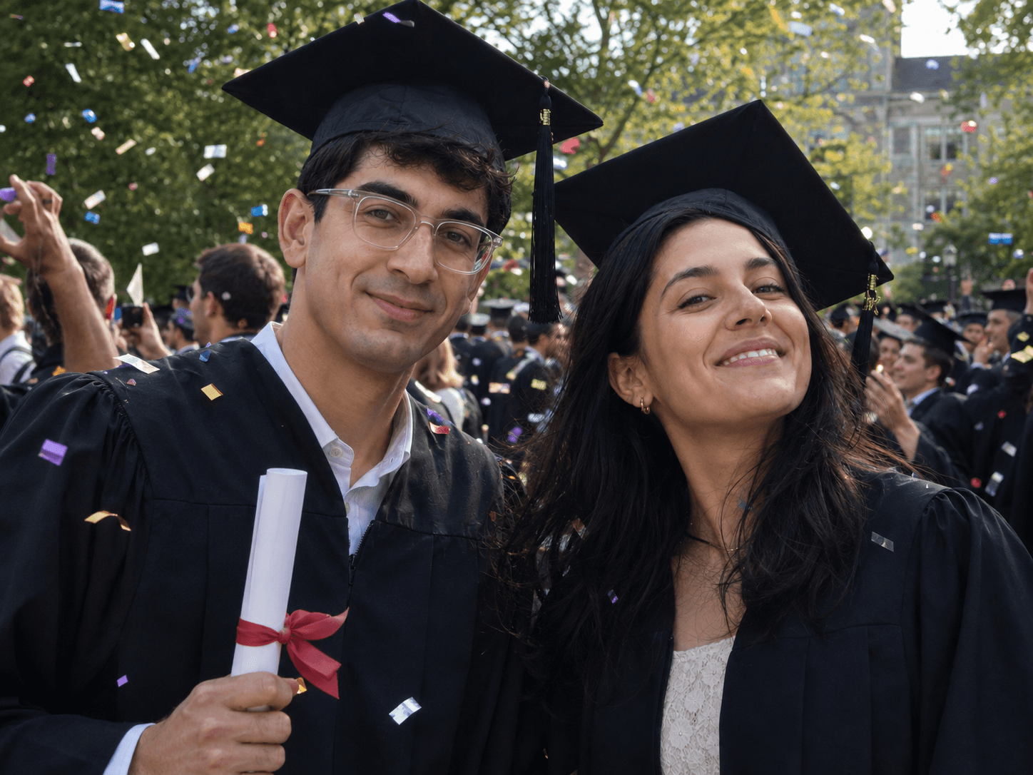 Two students celebrating in graduation caps and gowns